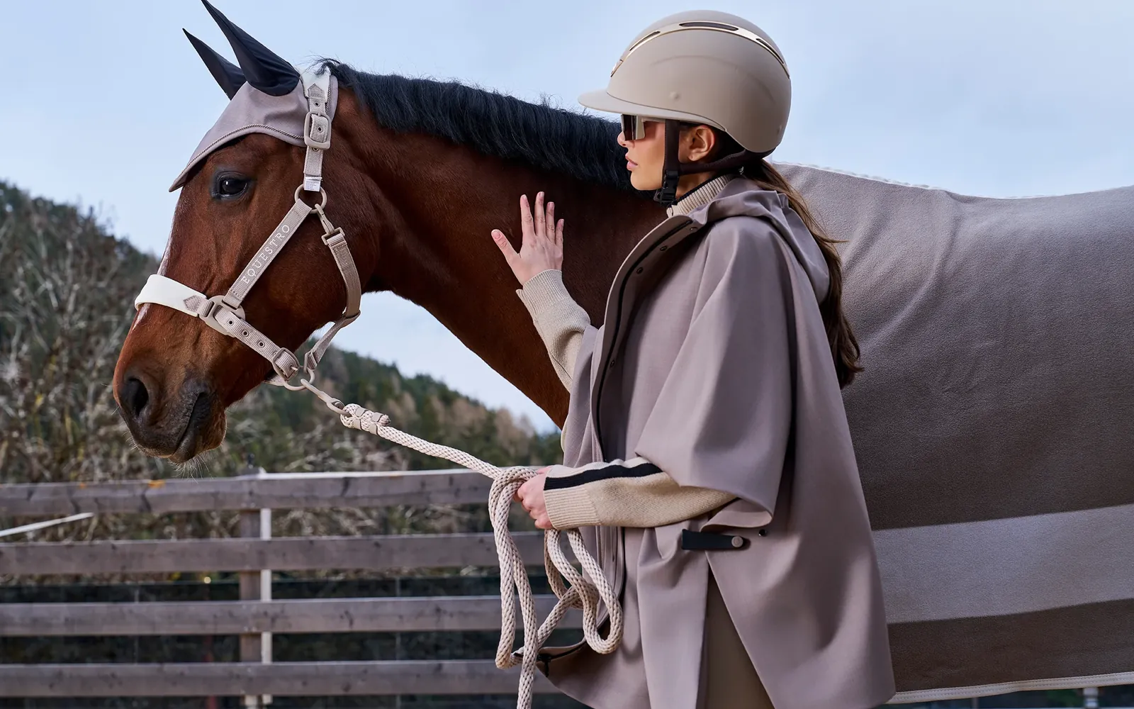 Equestro Herbst/Winter 2026: Pferd mit Fliegenhaube und Reiterin mit Helm und Poncho