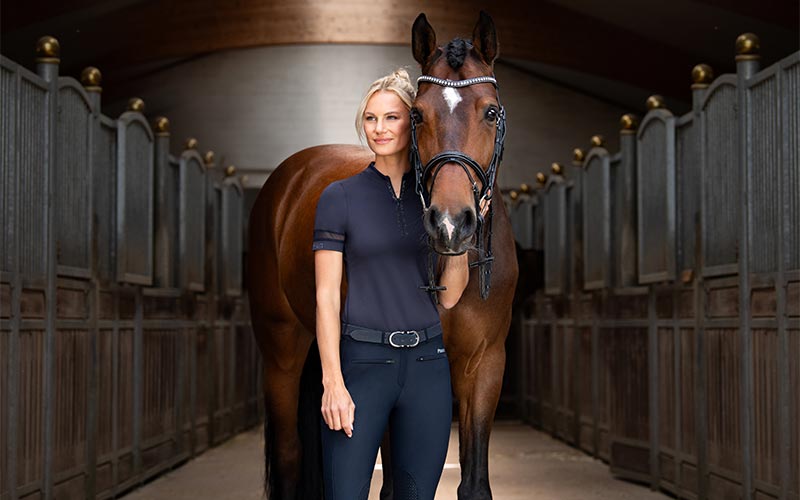 Pikeur Basic Line Pikeur Basic Line Bekleidung mit Frau und Pferd in Stallgasse